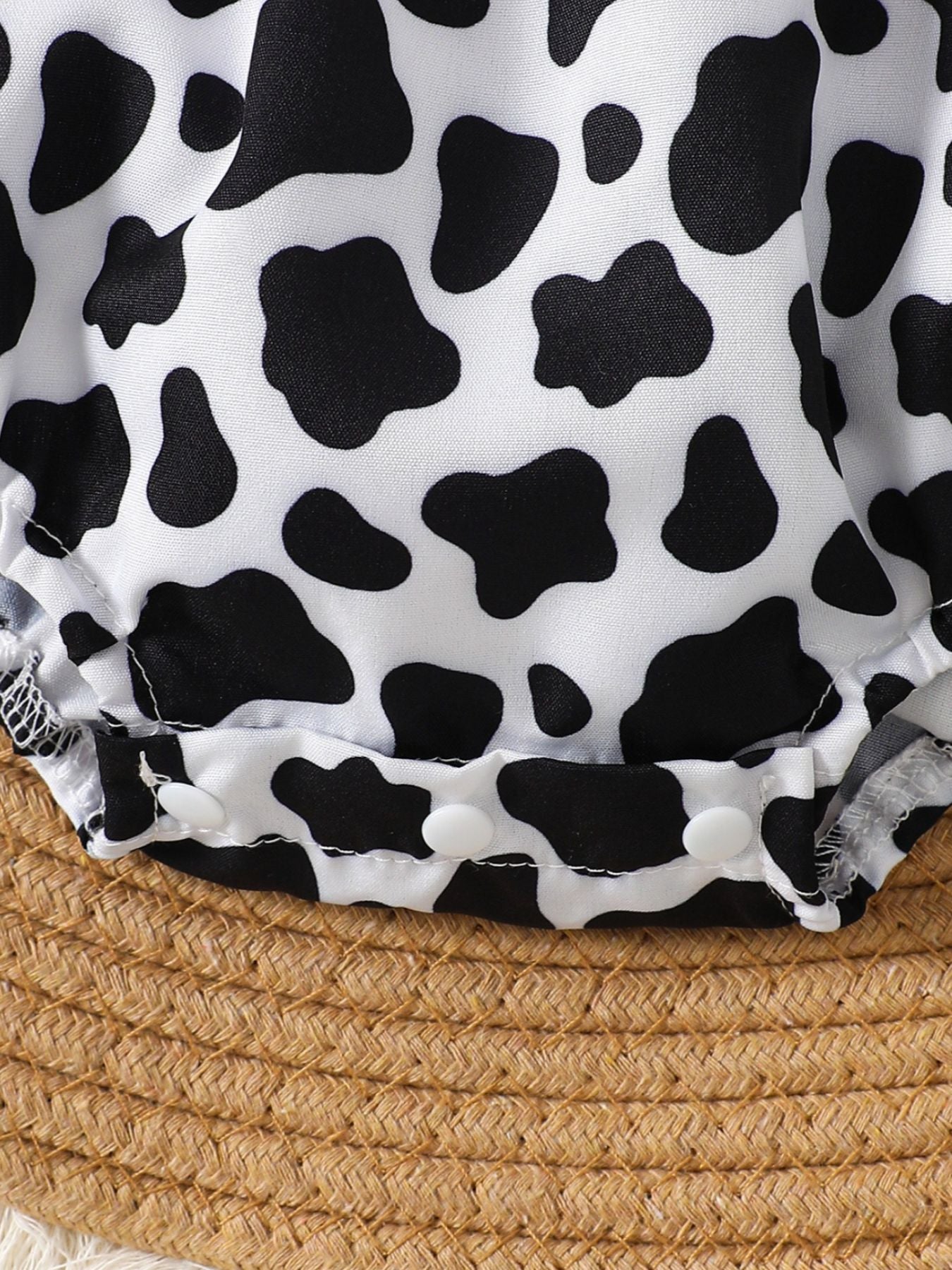 “Ruffle trim cow print baby one‑piece close‑up”