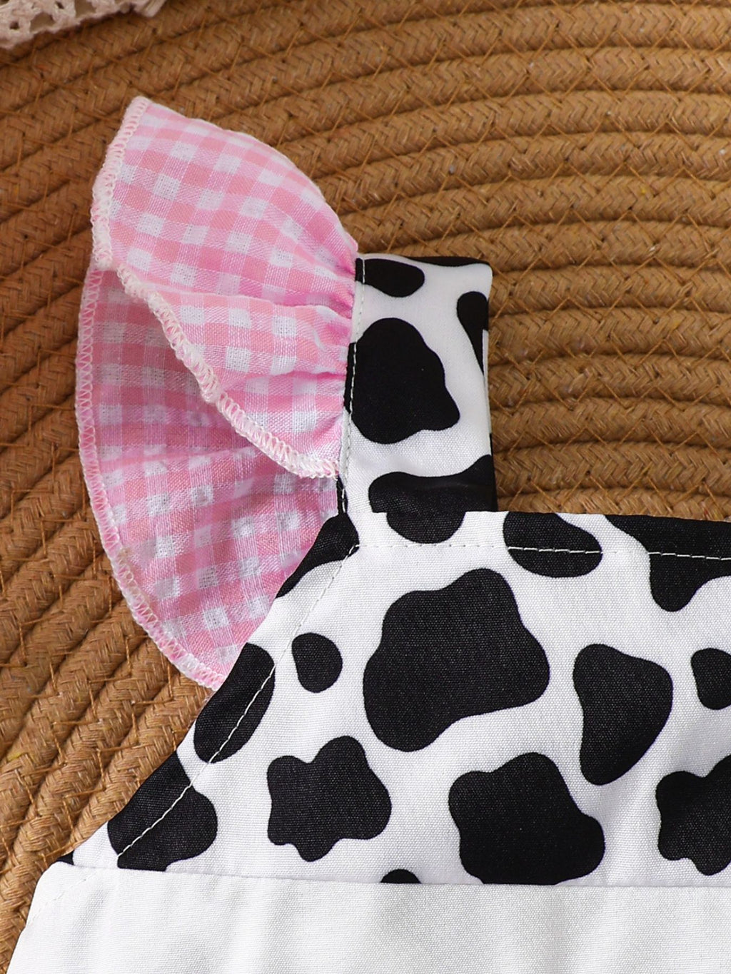 “Cow print baby romper with ruffle details, blush pink